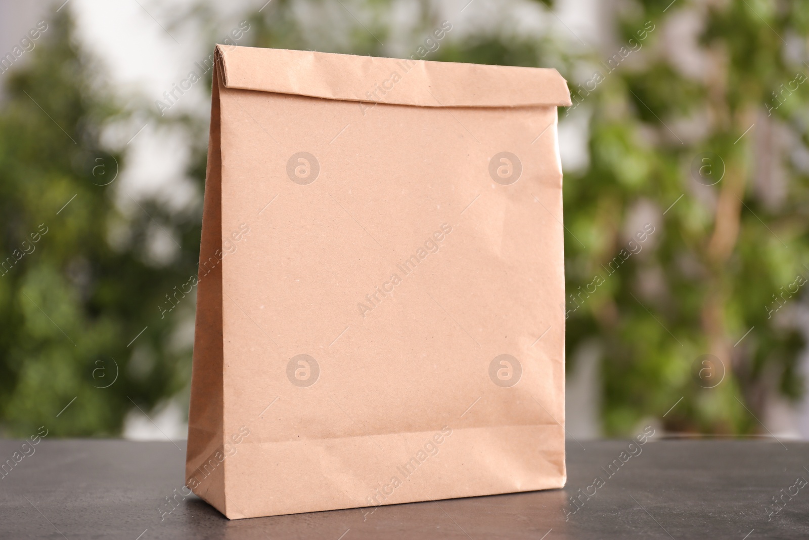 Photo of Blank paper bag on table against blurred background. Mock up for design