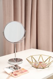 Photo of Dressing table with mirror, cosmetic products and jewelry in makeup room