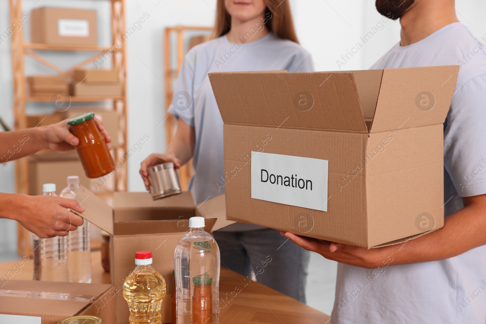 Photo of Group of volunteers packing food products in warehouse, closeup