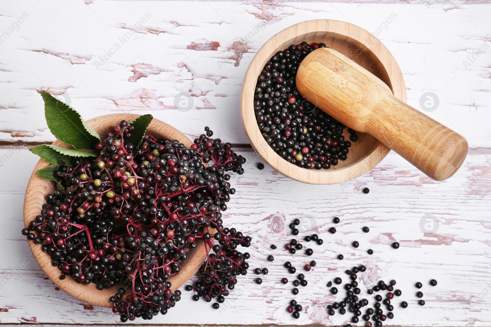 Photo of Tasty elderberries (Sambucus) on white wooden table, flat lay