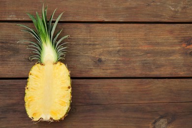 Half of ripe pineapple on wooden table, top view. Space for text
