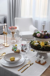 Photo of Beautiful Easter table setting with burning candles and floral decor indoors