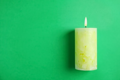 Photo of Alight wax candle and space for text on color background