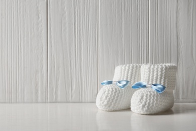 Photo of Handmade baby booties on table against wooden background. Space for text