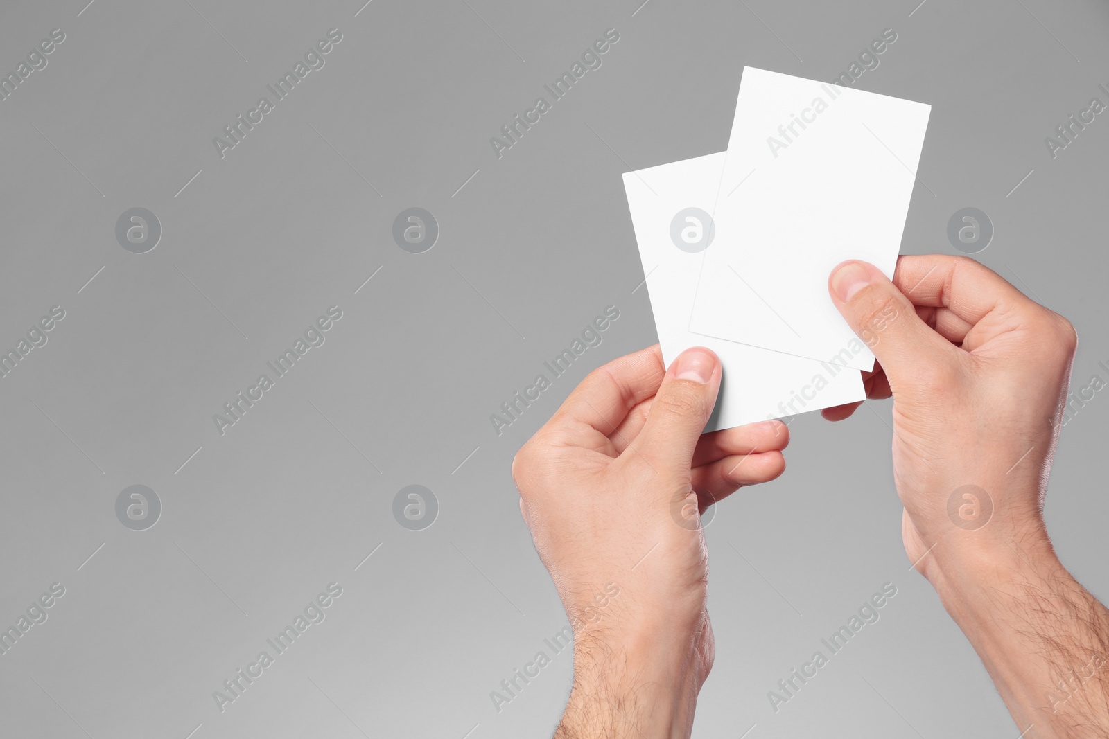 Photo of Man holding paper cards on grey background, closeup. Mockup for design