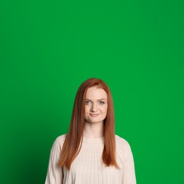 Image of Chroma key compositing. Pretty young woman with red hair against green screen