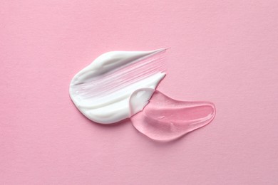 Photo of Samples of transparent gel and white cream on pink background, flat lay