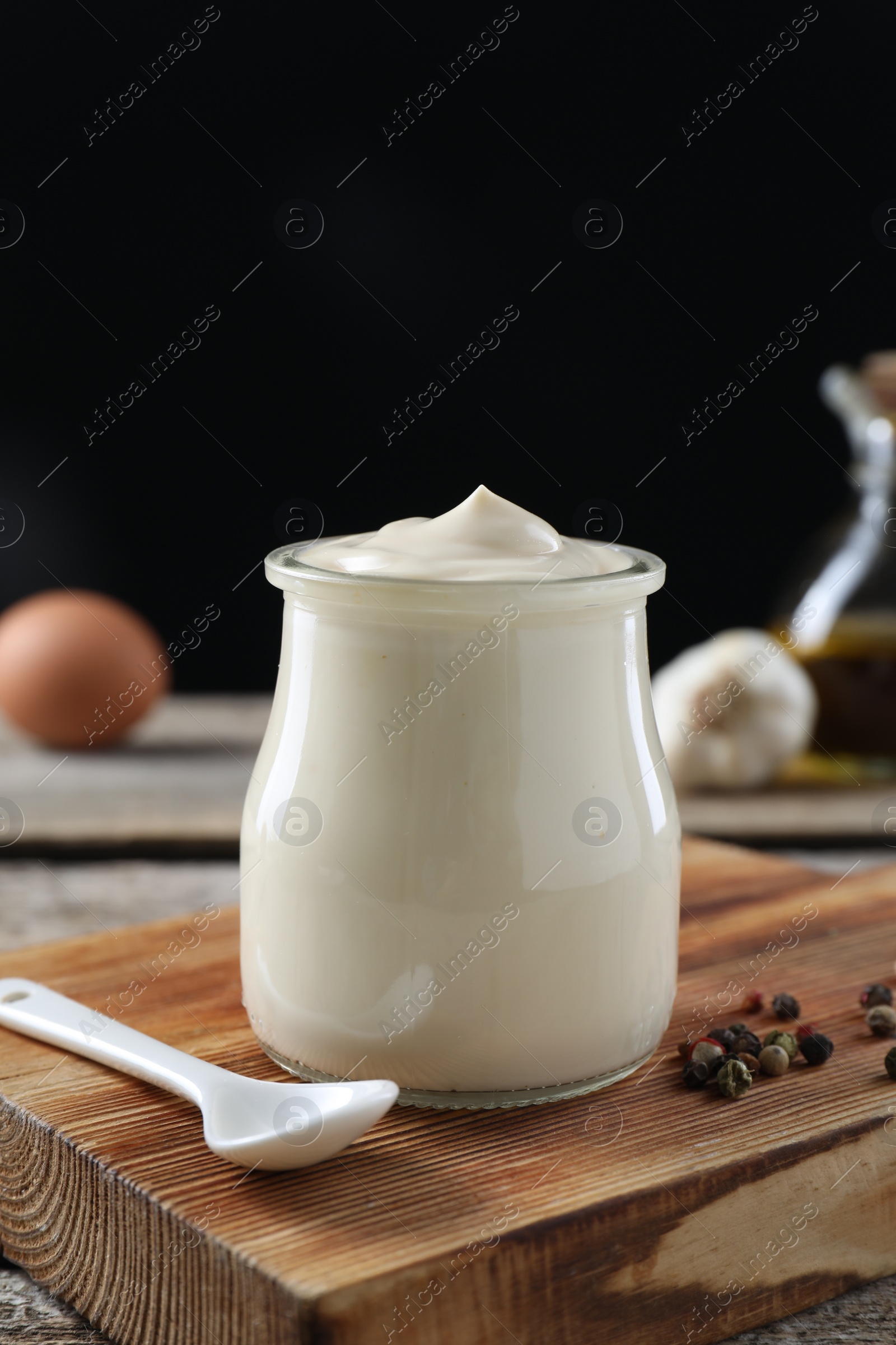 Photo of Fresh mayonnaise sauce in glass jar on wooden table, closeup