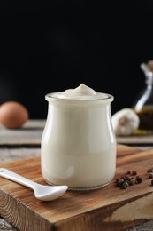 Photo of Fresh mayonnaise sauce in glass jar on wooden table, closeup