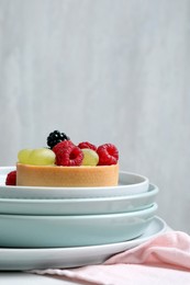 Photo of Delicious tartlet with berries on table against light background