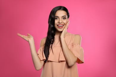 Portrait of surprised woman on pink background