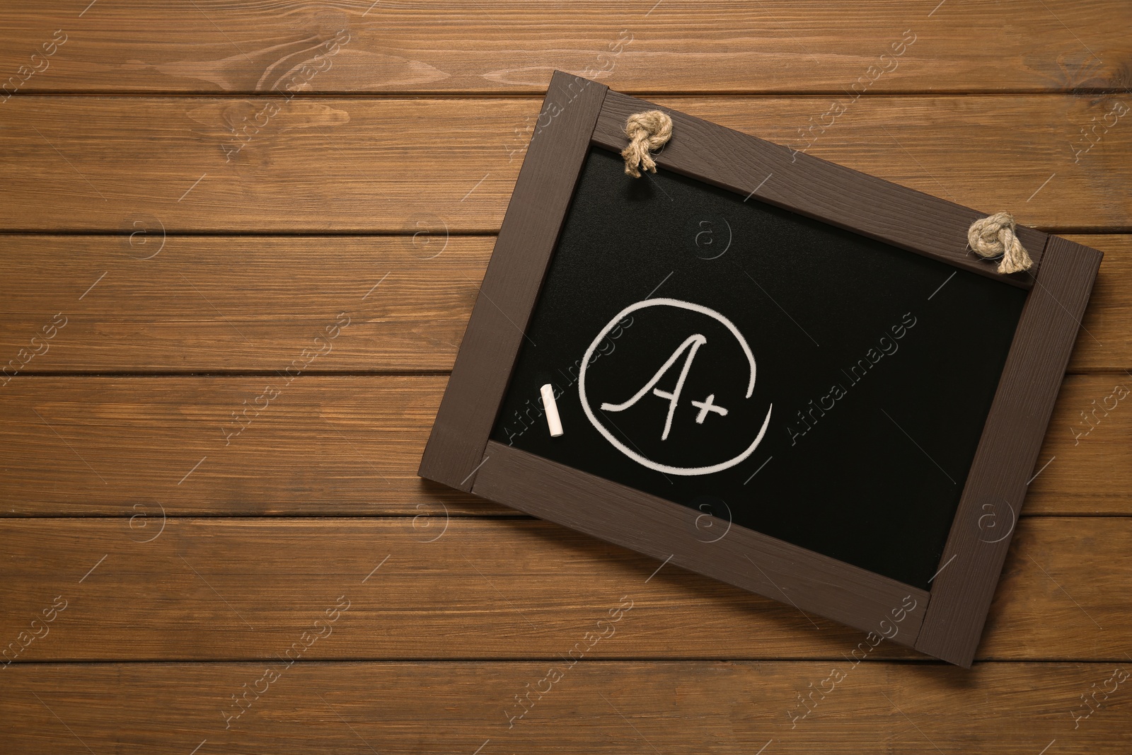 Image of School grade. Small blackboard with chalked letter A and plus symbol on wooden background, top view