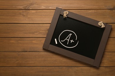 School grade. Small blackboard with chalked letter A and plus symbol on wooden background, top view