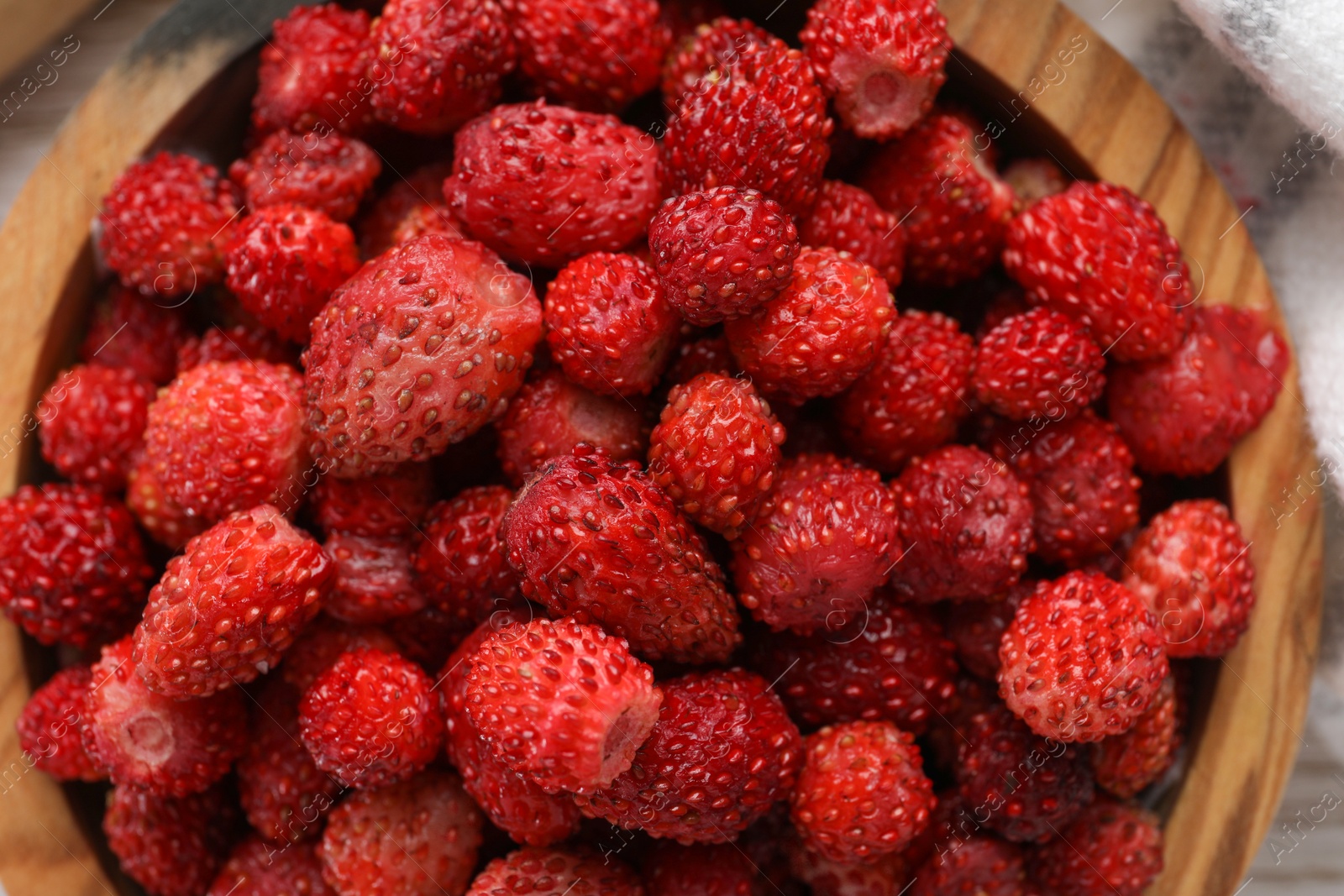 Photo of Fresh wild strawberries in bowl on table, top view