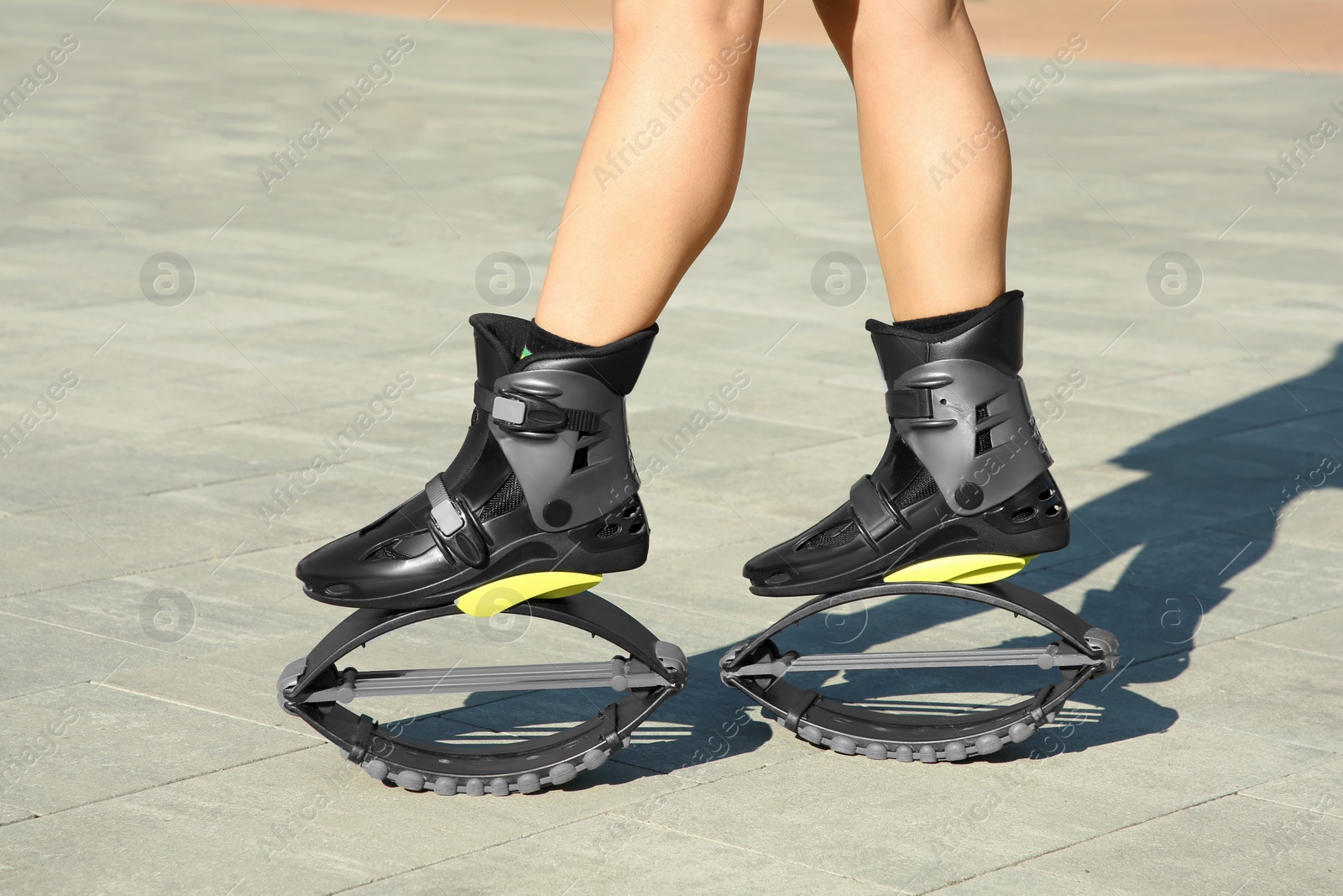 Photo of Woman in kangoo jumping boots outdoors on sunny day, closeup