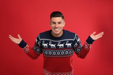 Happy man in Christmas sweater on red background