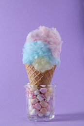 Sweet cotton candy in waffle cone on purple background