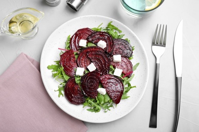 Photo of Roasted beetroot slices with feta cheese and arugula served on light grey table, flat lay