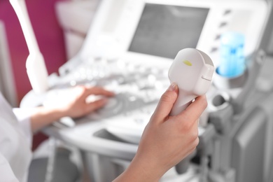 Photo of Sonographer holding ultrasound machine probe in clinic, closeup