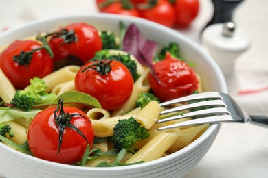 Photo of Bowl of delicious pasta with tomatoes, arugula and broccoli, closeup