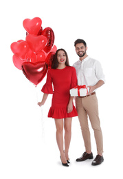 Photo of Happy young couple with gift box and heart shaped balloons isolated on white. Valentine's day celebration