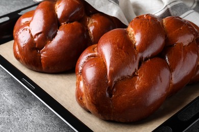 Photo of Homemade braided bread on grey table, closeup. Traditional challah