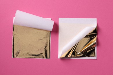 Photo of Edible gold leaf sheets on pink background, flat lay