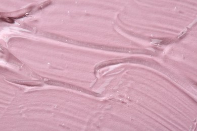 Clear cosmetic serum on pink background, macro view