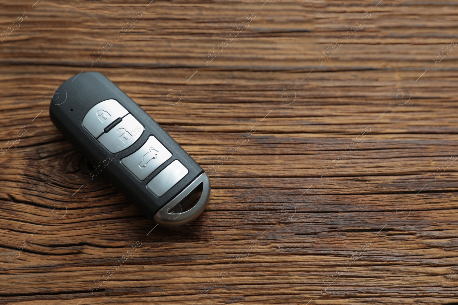 Photo of Remote car key on wooden background, top view. Space for text