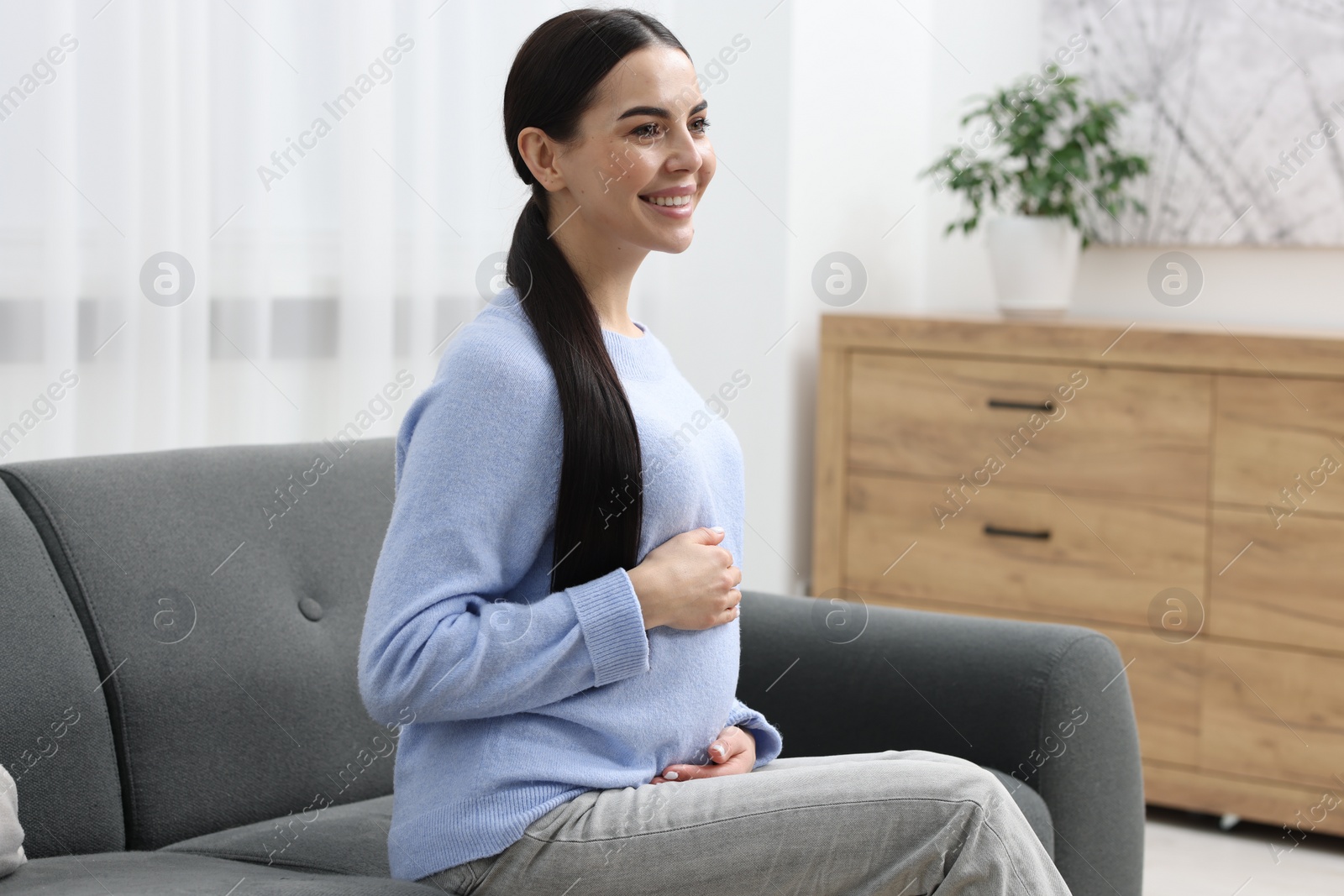 Photo of Happy pregnant woman on sofa at home