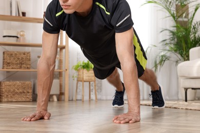 Photo of Man doing high plank exercise on floor at home, closeup