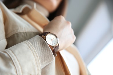 Photo of Woman with luxury wristwatch on blurred background, closeup