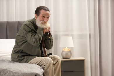 Photo of Senior man with walking cane on bed at home