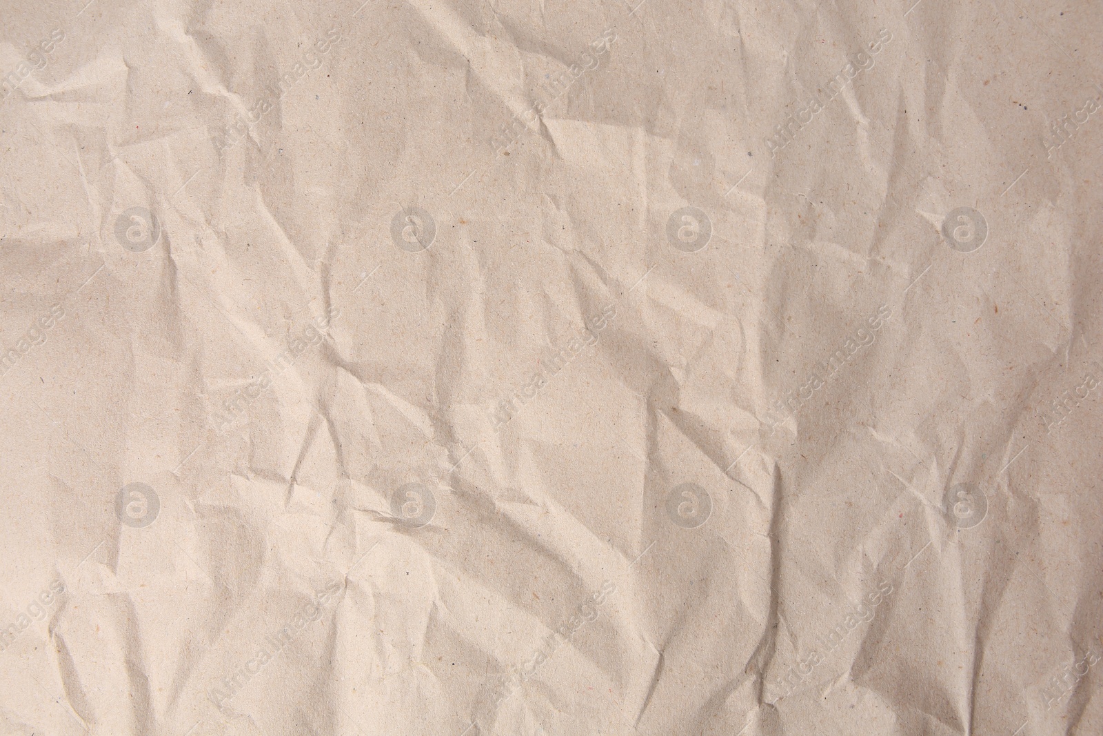 Photo of Sheet of crumpled light brown paper as background, top view