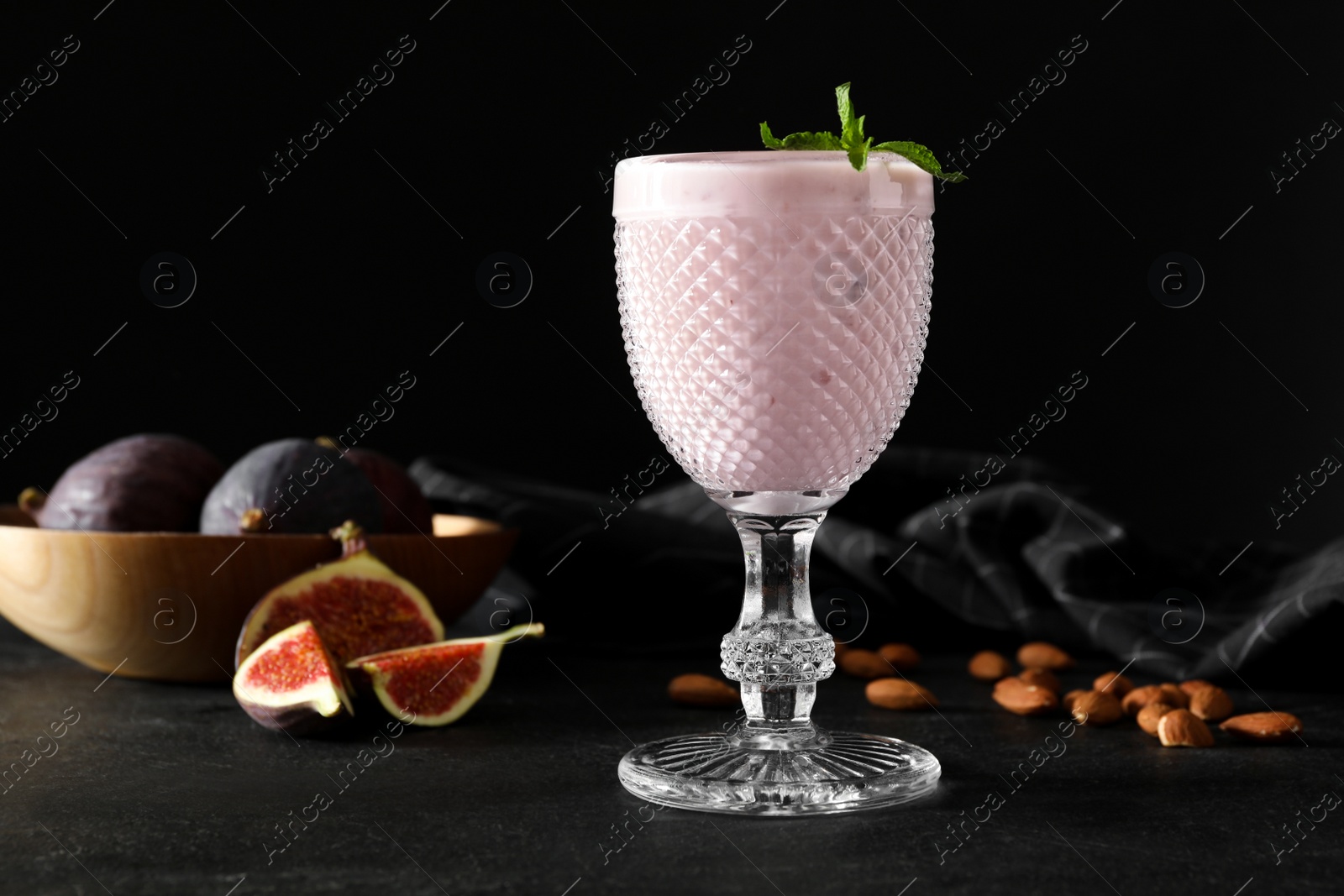 Photo of Delicious fig smoothie in glass on black table