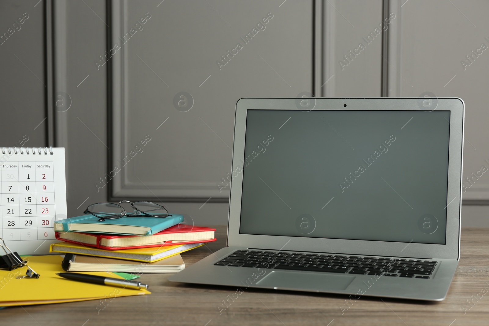 Photo of Modern laptop and office supplies on wooden table indoors. Distance learning