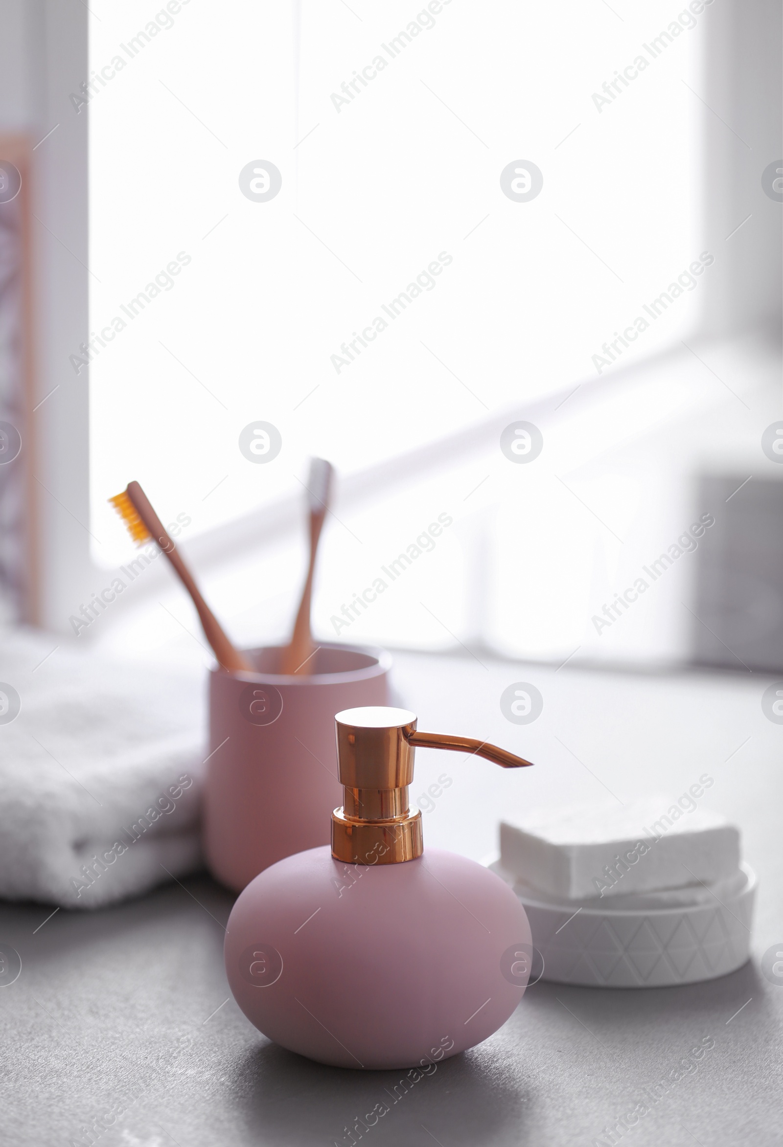 Photo of Bottle with liquid soap and toiletries on table against blurred background. Space for text