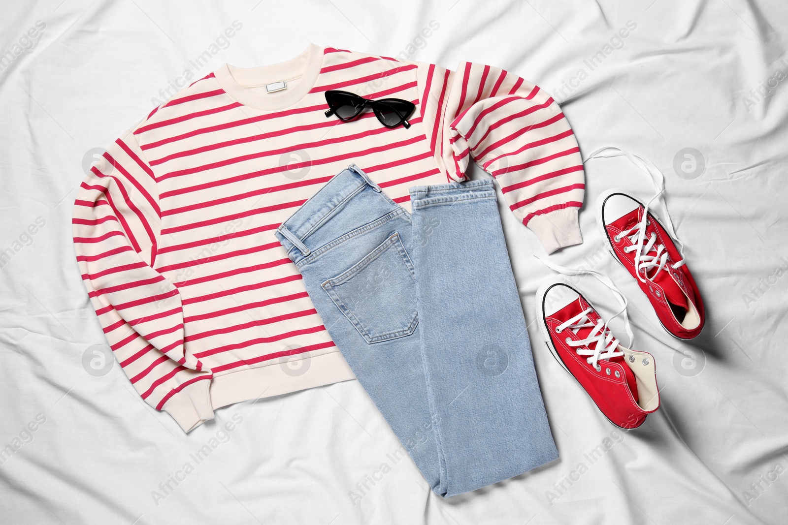 Photo of Pair of stylish red shoes, clothes and sunglasses on white fabric, flat lay