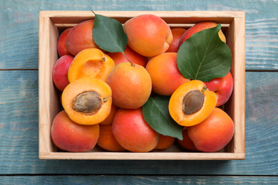 Photo of Delicious fresh ripe apricots on blue wooden table, top view