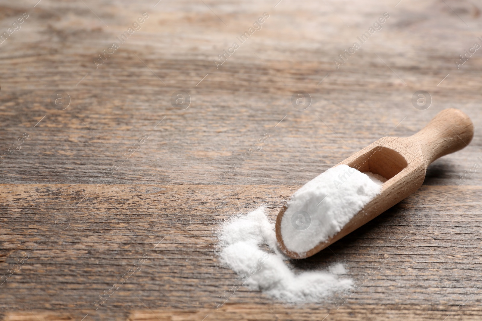 Photo of Scoop with baking soda on wooden table