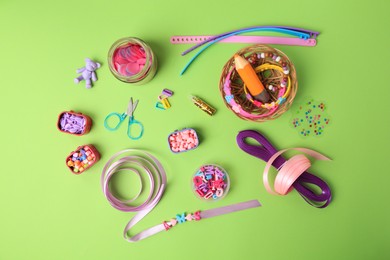 Handmade jewelry kit for children. Colorful beads, ribbons and supplies on green background, flat lay