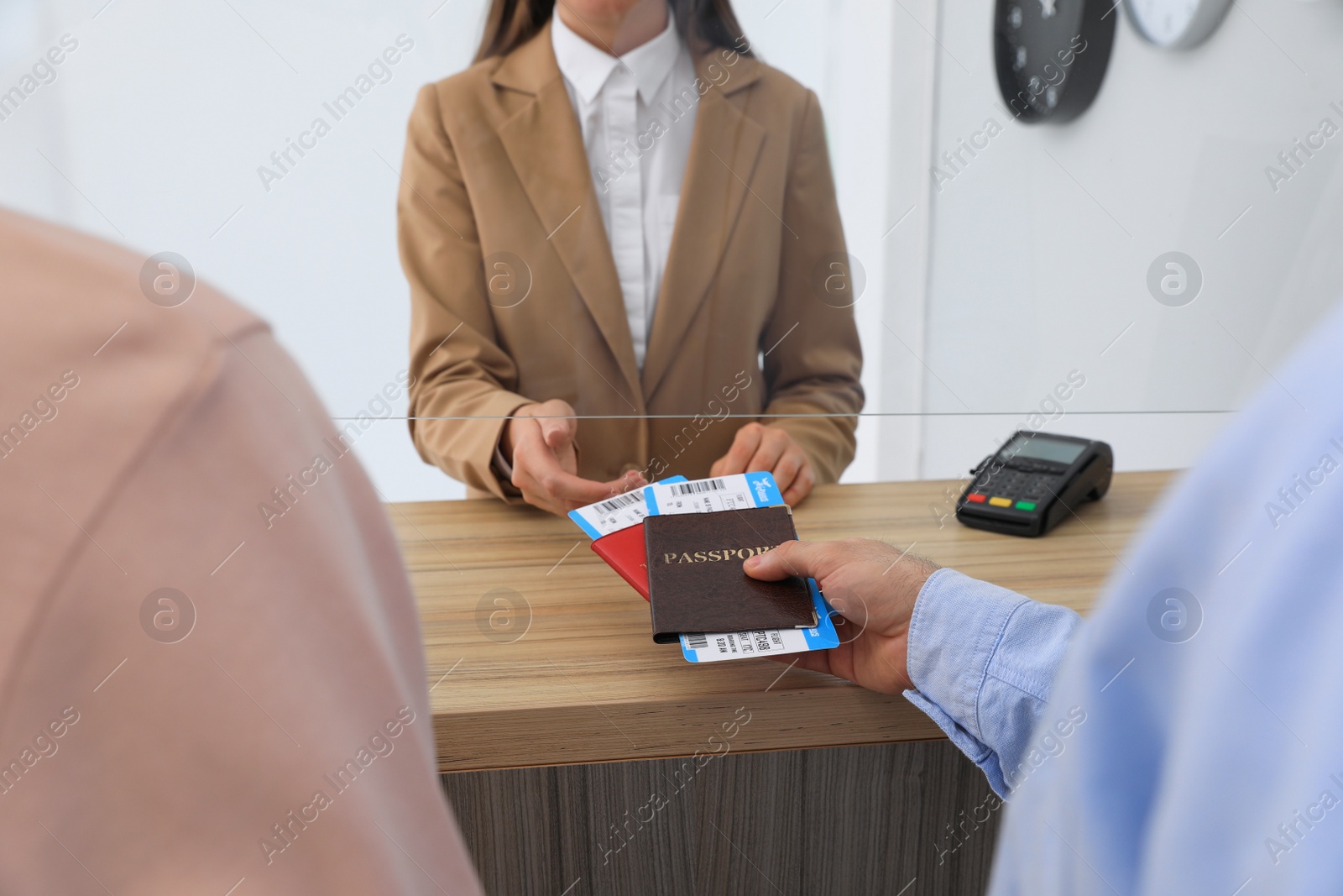 Photo of Man giving passports with tickets to agent at check-in desk in airport, closeup