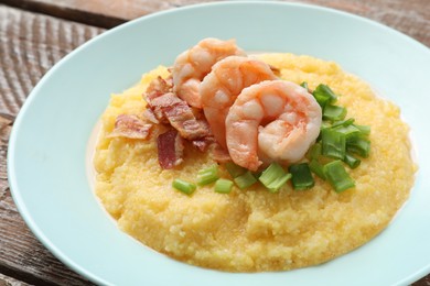 Photo of Plate with fresh tasty shrimps, bacon, grits and green onion on wooden table, closeup