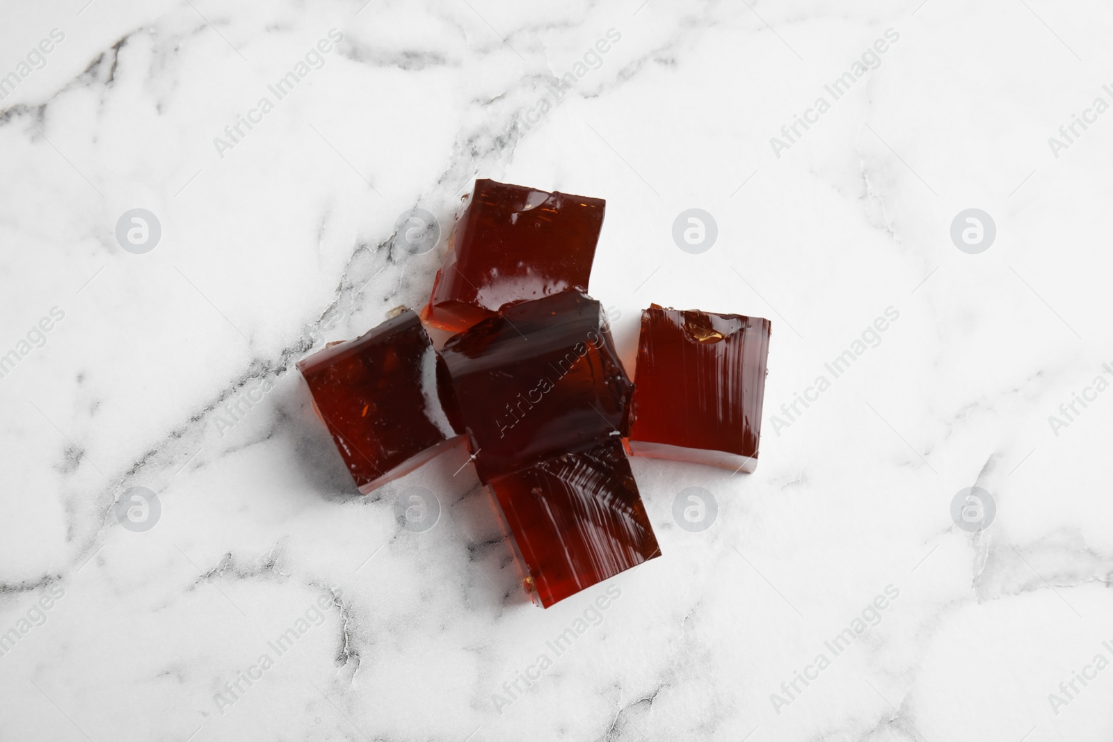 Photo of Heap of delicious grass jelly cubes on white marble table, flat lay