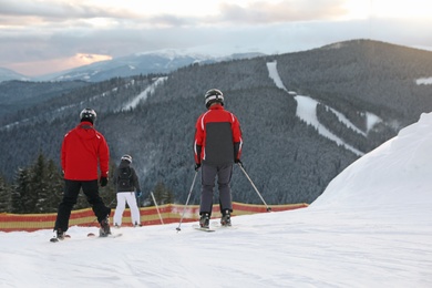 People skiing on snowy hill in mountains. Winter vacation