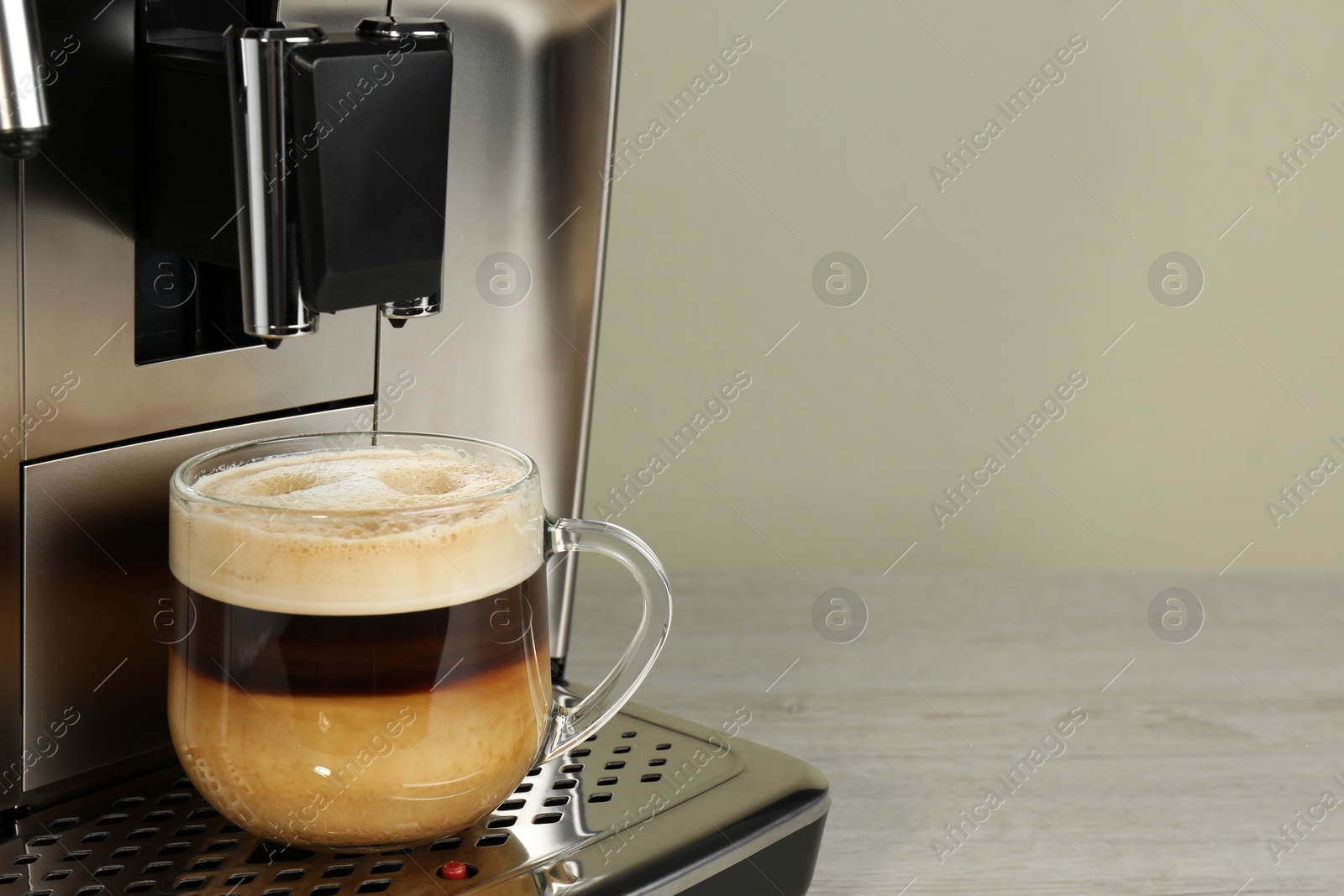 Photo of Modern coffee machine with glass cup of latte on wooden table, closeup. Space for text