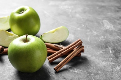 Fresh apples and cinnamon sticks on gray table