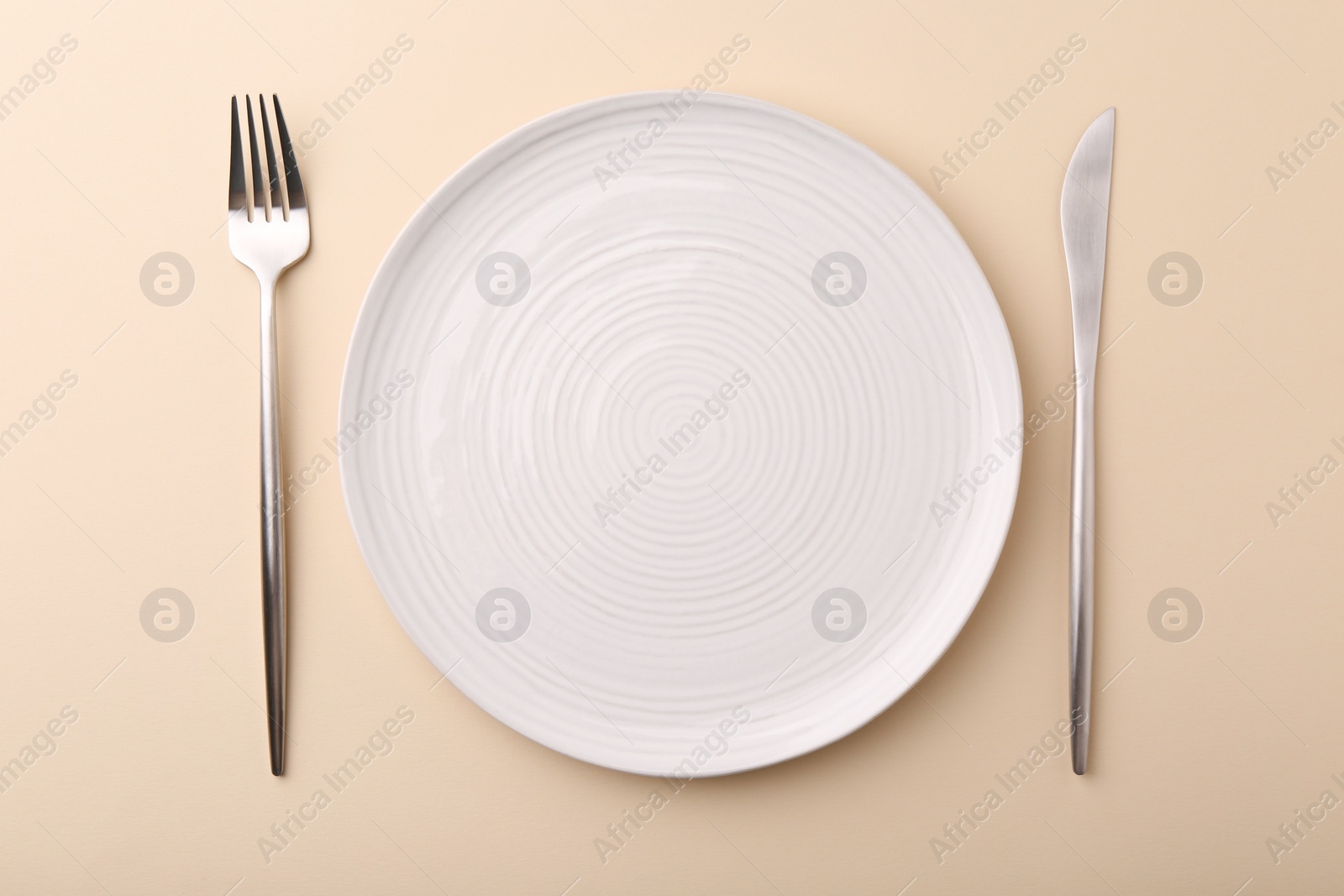 Photo of Setting with stylish cutlery on beige table, top view