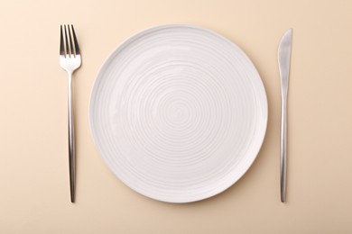 Photo of Setting with stylish cutlery on beige table, top view