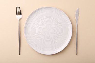 Setting with stylish cutlery on beige table, top view